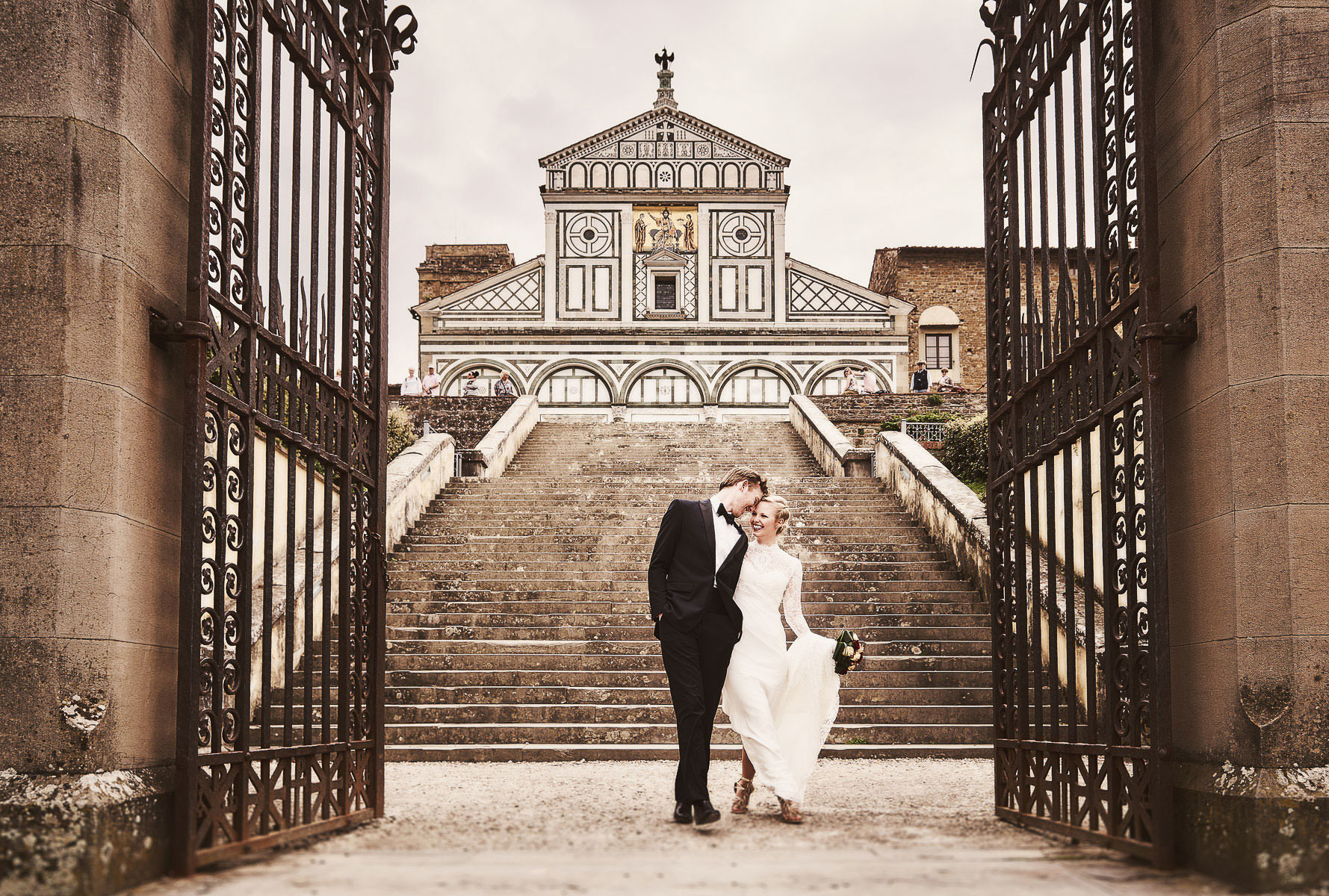 Bride and groom walk through the gate of San Miniato a Monte near Piazzale Michelangelo Florence