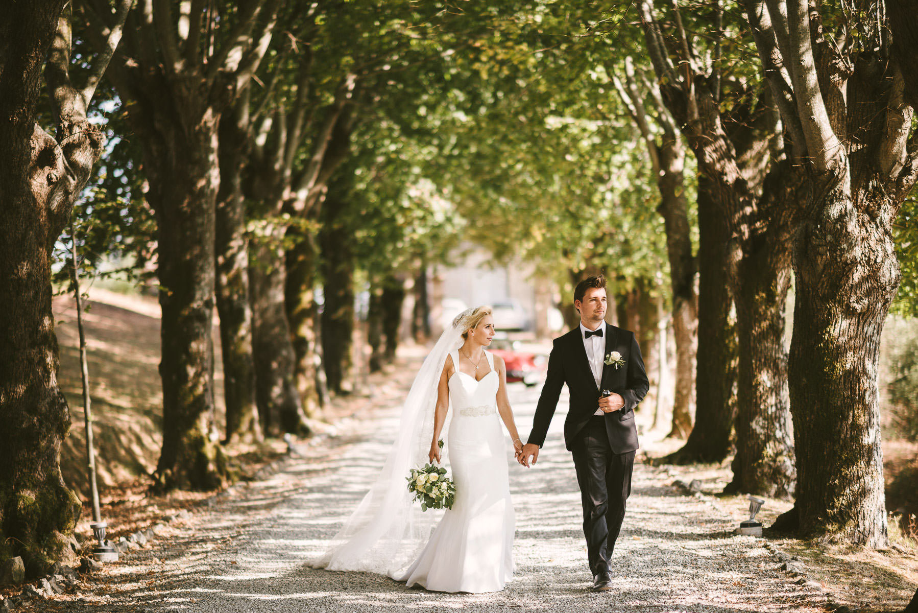 Bride and groom walk into the lovely street of Borgo di Colleoli into the Tuscany countryside