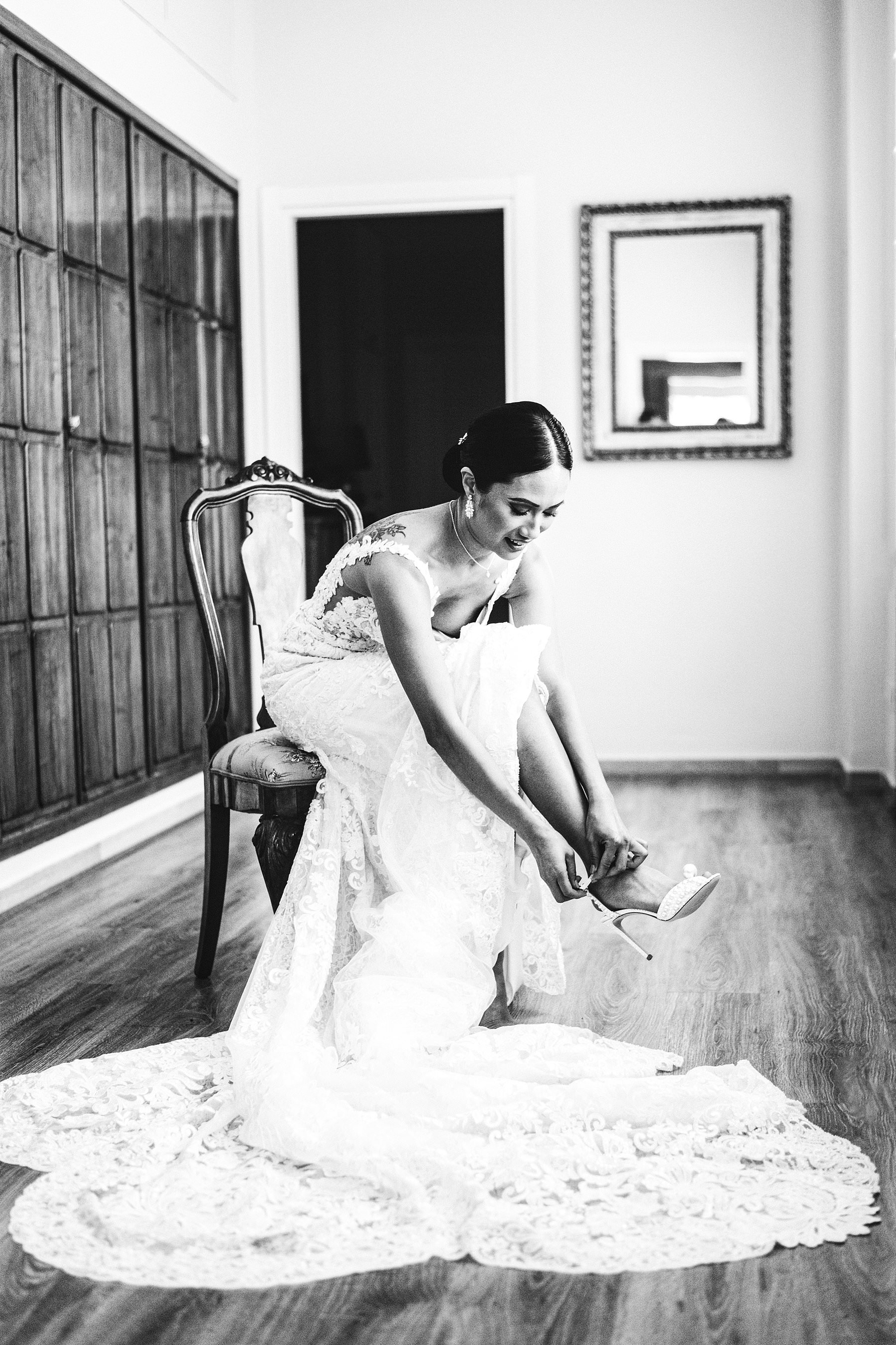 Gorgeous bride Liza in her luxury and beautiful Martina Liana wedding gown putting her Jimmy Choo shoes during the getting ready