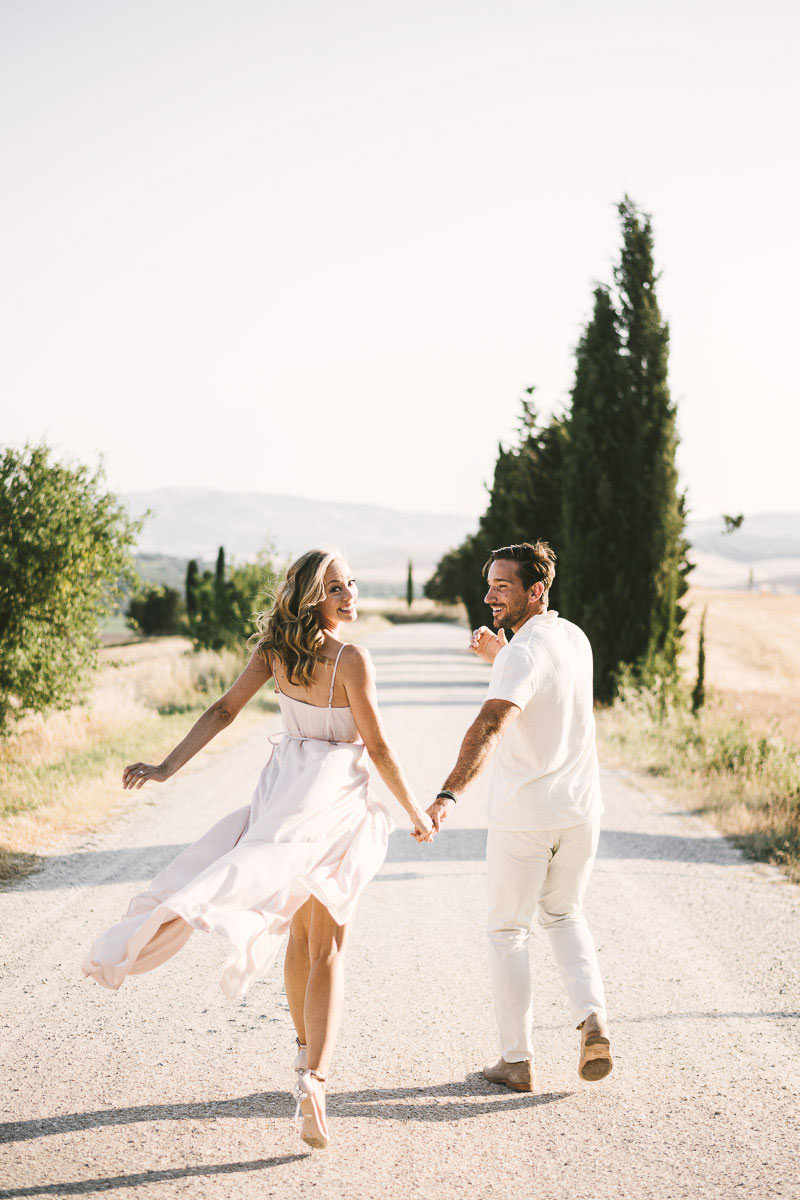 Romantic, intimate and elegant engagement photo shoot in Tuscany countryside of Pienza in the Val D'Orcia area with cypresses street and rolling hills as background