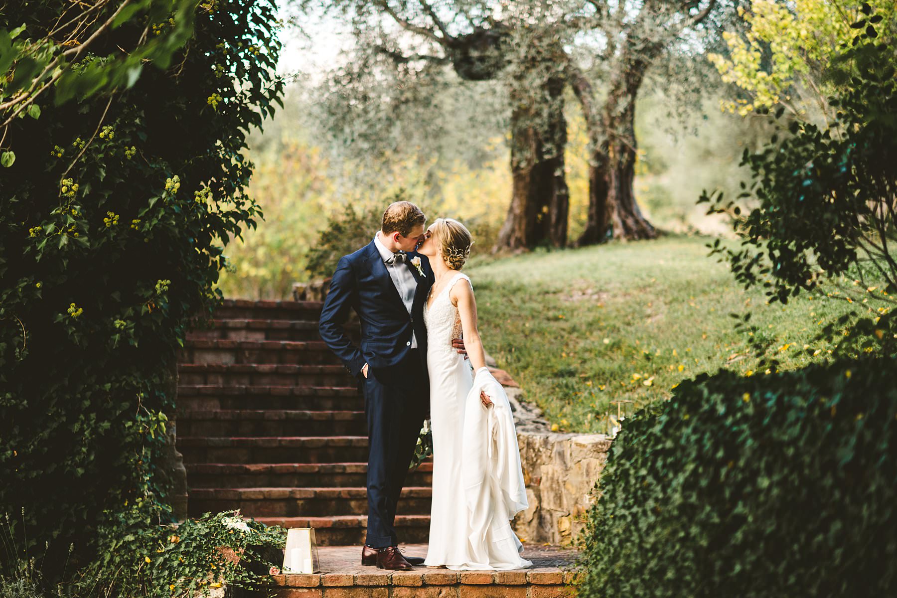 A special international wedding in the countryside of Umbria, Italy. Elegant Australian wedding couple portrait around the property of Villa Monte Solare, a historic residence tucked in the countryside among rolling hills. The settings were countryside landscapes with cypress lines, olive groves and a stunning wall covered in red ivy leaves