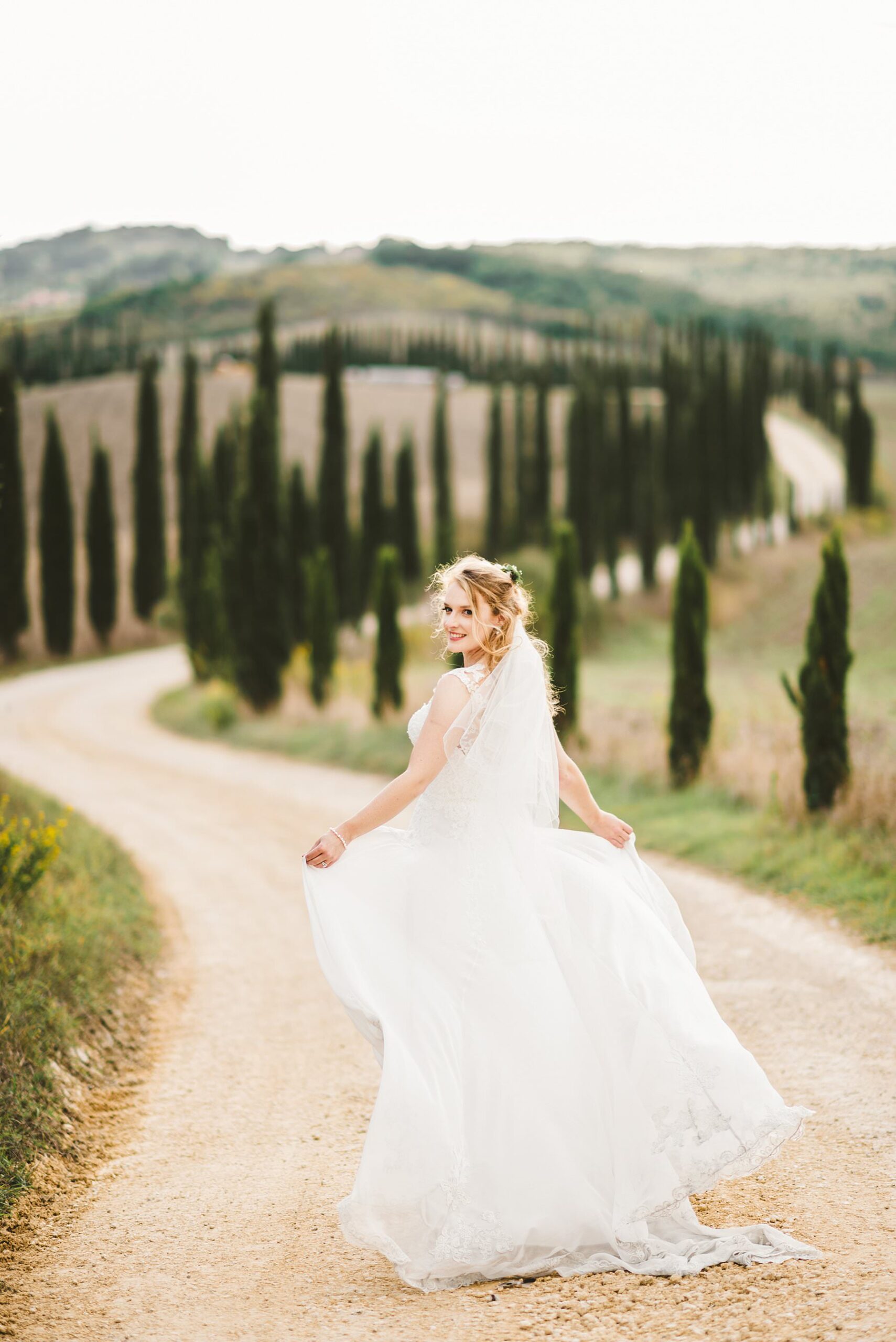 Destination elopement wedding in Tuscany. Lovely and elegant bride in Justin Alexander gown during a walk tour in the most iconic, evocative and stunning countryside views