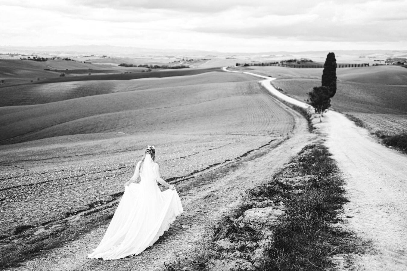 Gorgeous real bride in gorgeous Justine Alexander gown walks toward the evocative and iconic countryside of Tuscany near Siena