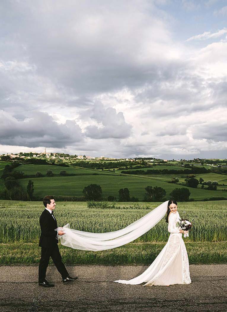 The amazing landscape of Umbria near the historic venue of Villa l’Antica Posta. Exciting bride in Grace Loves Lace with groom in their intimate destination wedding