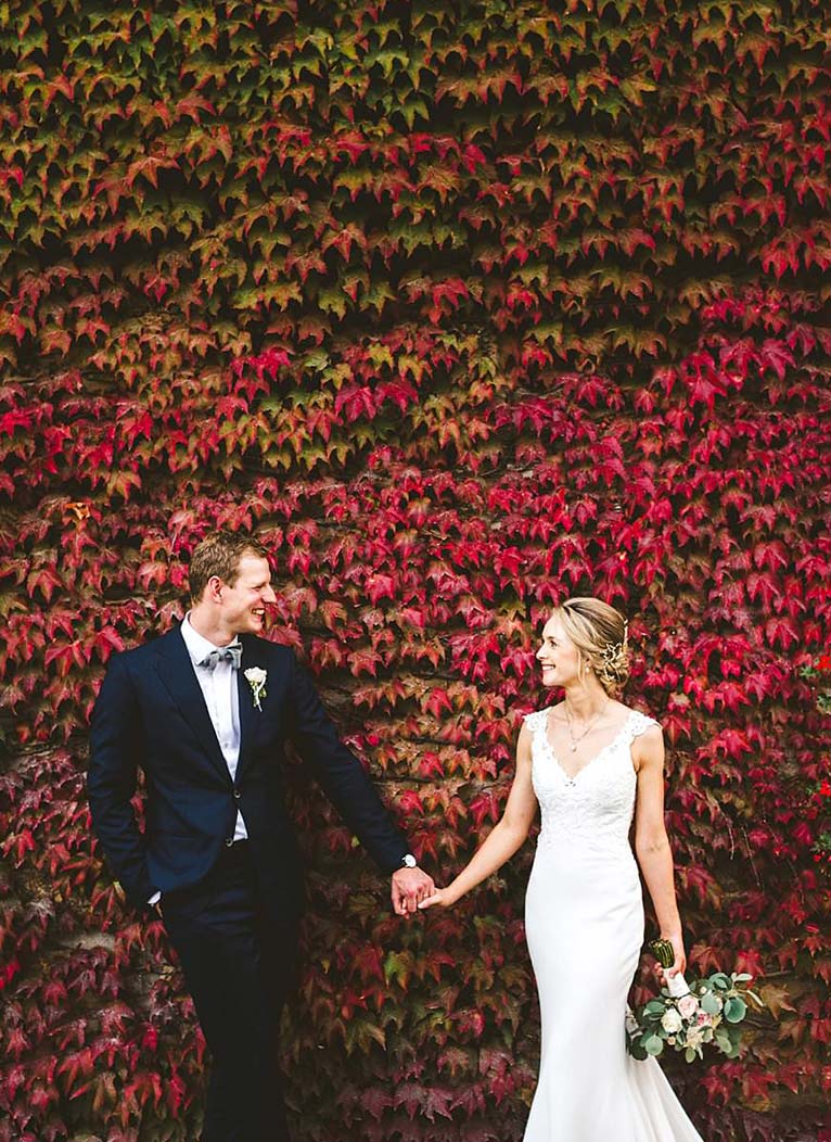 A special international wedding in the countryside of Umbria, Italy. This beautiful Australian couple dreamed this unforgettable day for a long time and finally they made it. Bride and groom portrait at stunning wall covered in red ivy leaves near Villa Monte Solare, a historic residence tucked in the countryside among rolling hills