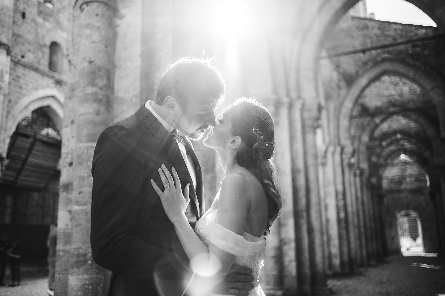 Romantic couple wedding portrait inside the gorgeous Roofless Abbey of San Galgano near Siena in the countryside of Tuscany