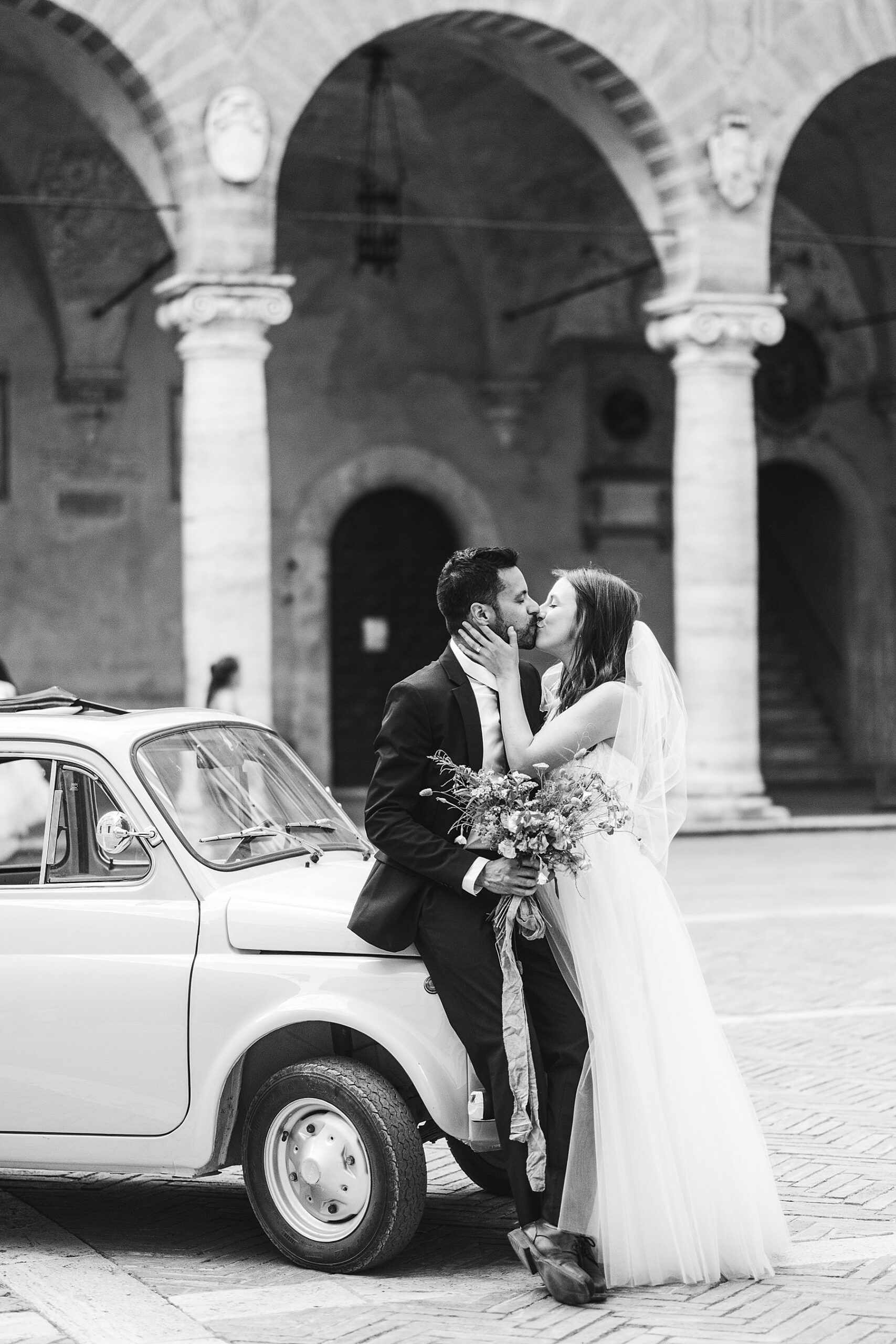 Bride and groom elopement portrait photo with Fiat 500 in the charming streets of Pienza, Tuscany