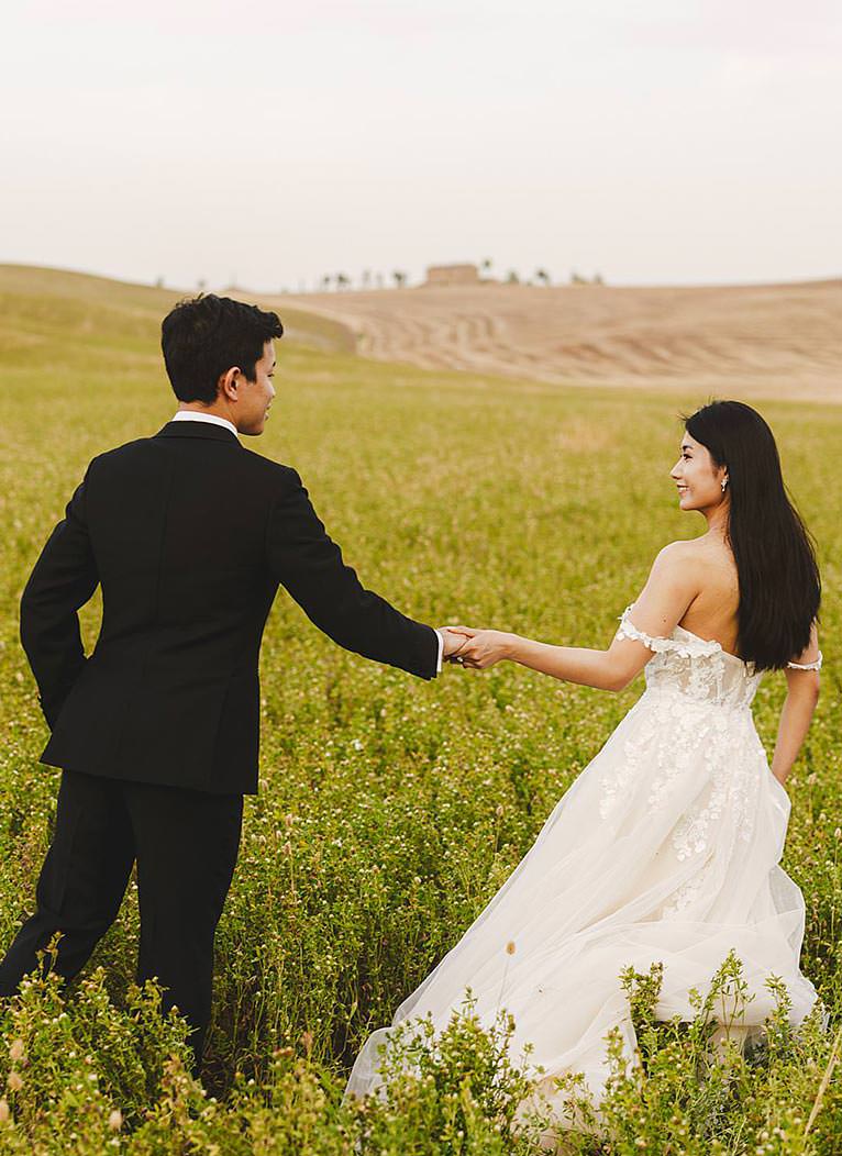 Romantic couple dressed with wedding dresses engagement pictures in iconic and dreaming countryside of picturesque village of Pienza heart of Tuscany