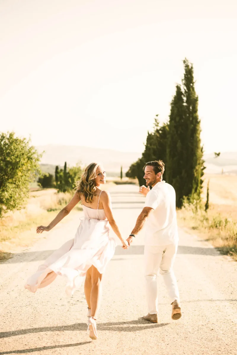Romantic, intimate and elegant engagement photo shoot in Tuscany countryside of Pienza in the Val D'Orcia area with cypresses street and rolling hills as background
