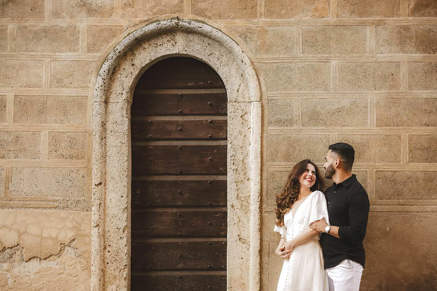 Smiling couple photo in the historic center of Pienza next to an ancient door