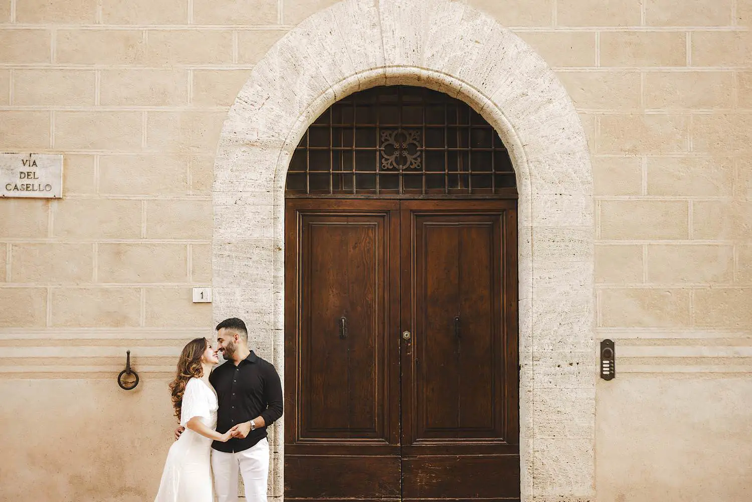 Smiling couple photo in the historic center of Pienza next to an ancient door