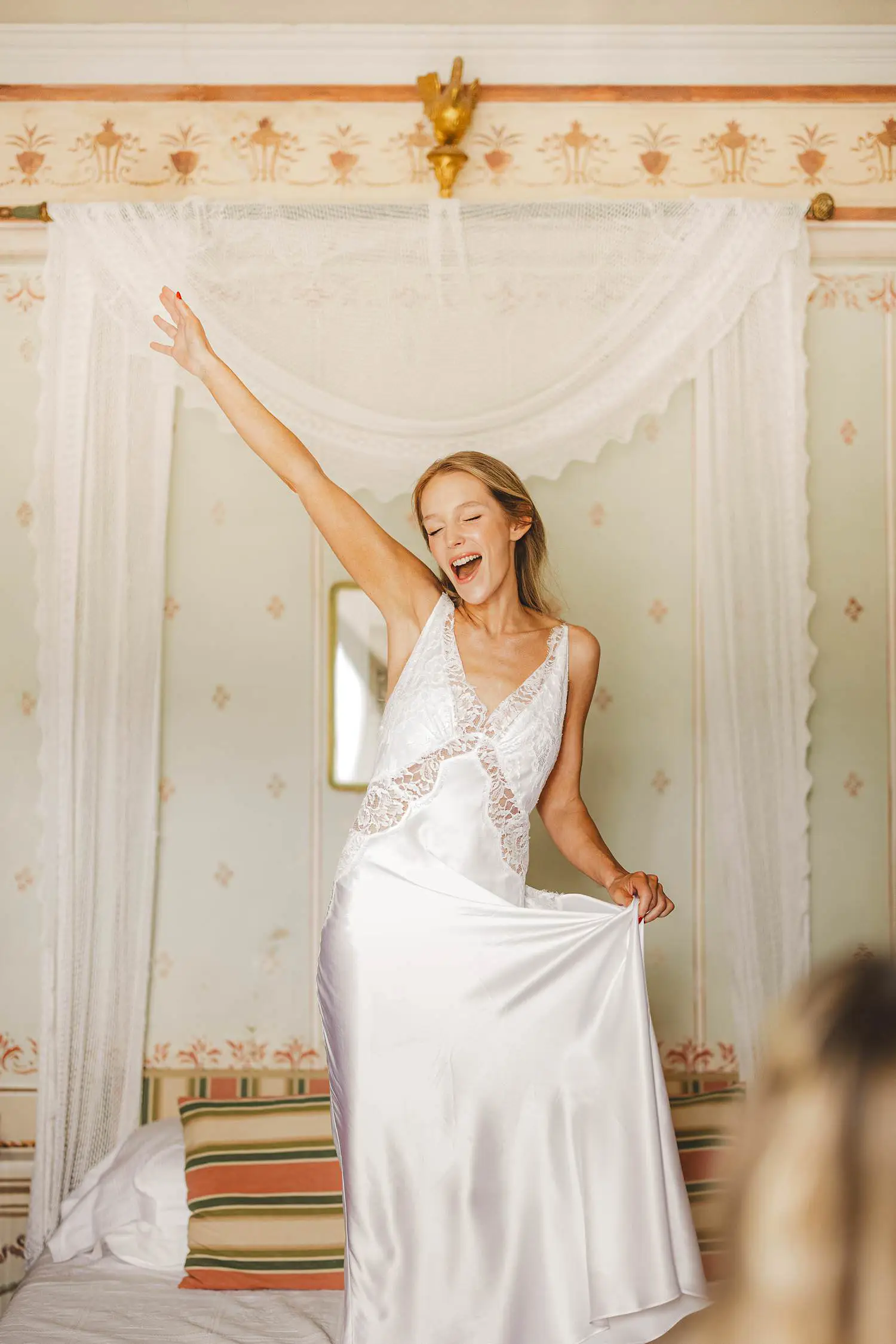 Smiling bride having fun and jumping on a bed in a castle suite at Castello di Celsa