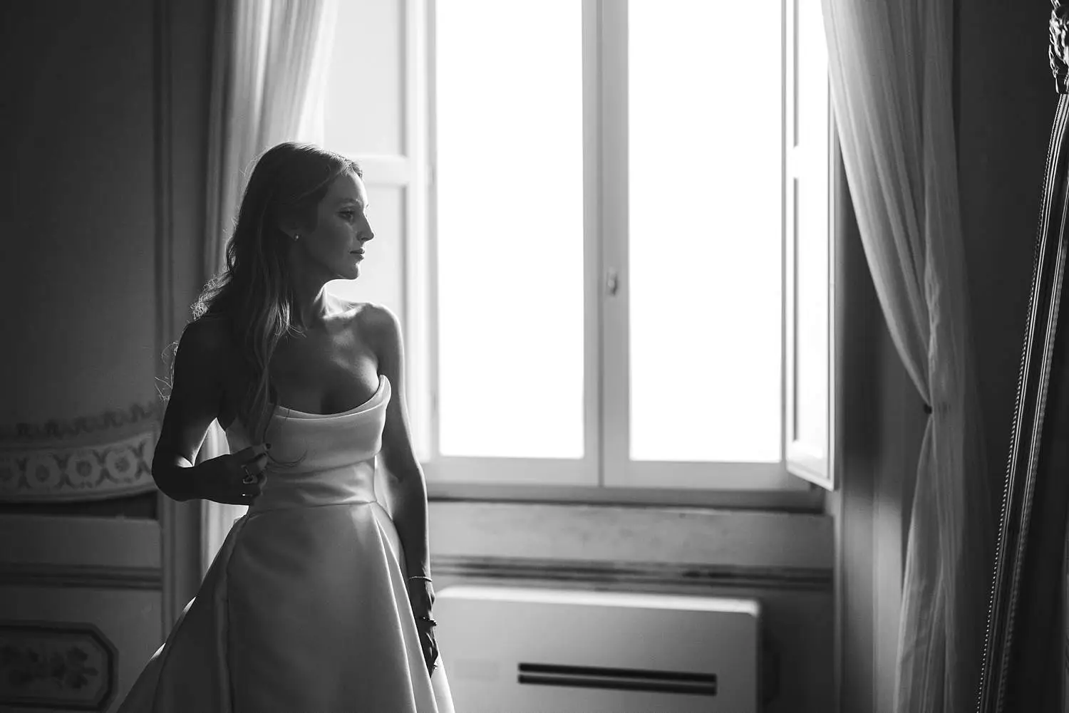 Elegant bride in gown candid photo while she’s looking herself in a mirror for the final touches at Castello di Celsa