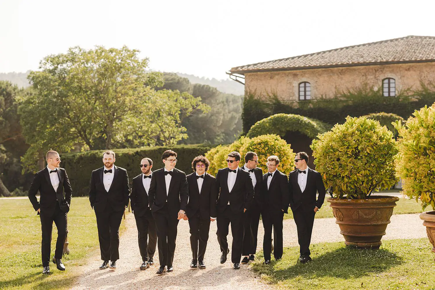 The groom shares a relaxed walk with his best men in the scenic grounds of Castello di Celsa