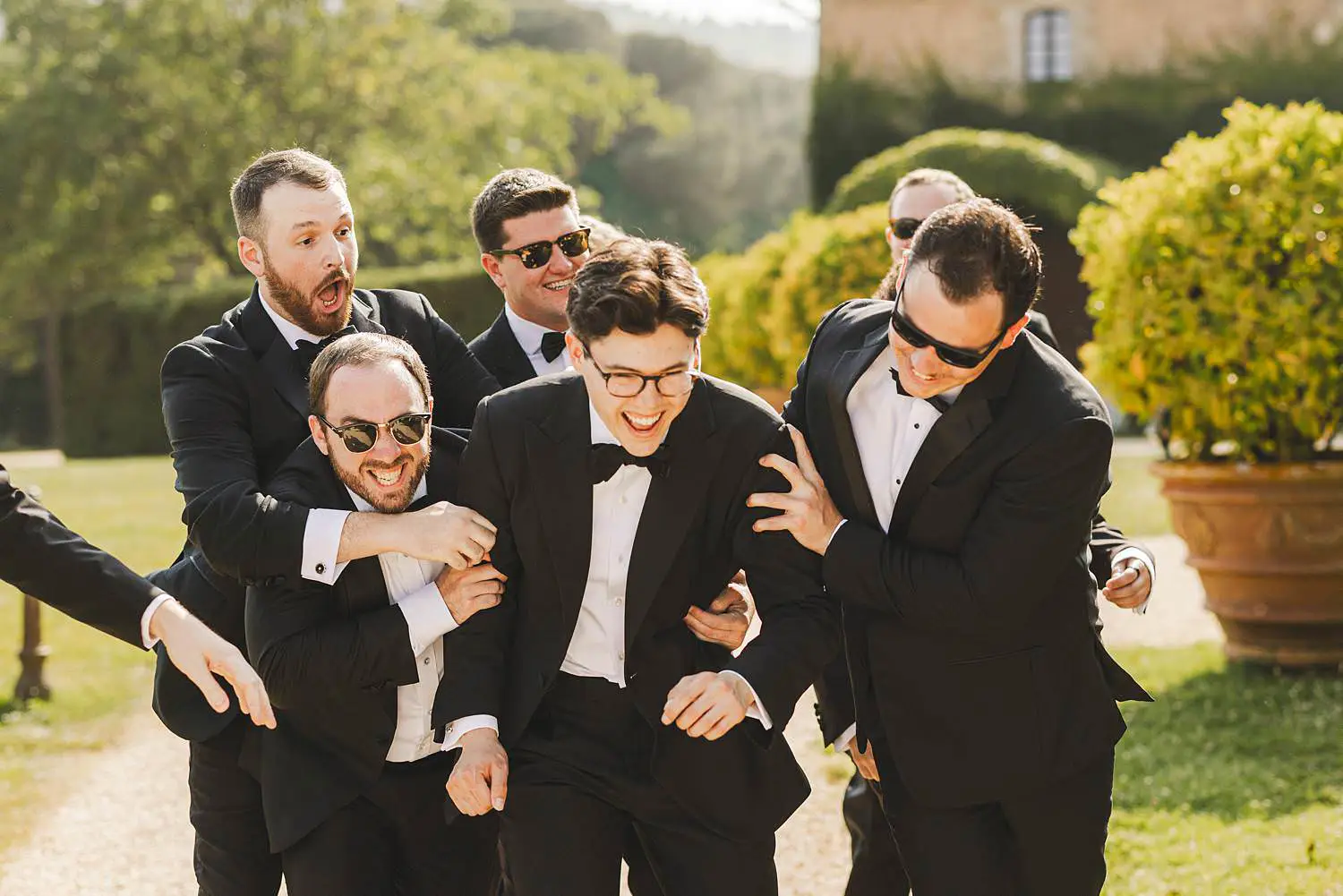 The groom shares a joyful moment with his best men in the scenic grounds of Castello di Celsa