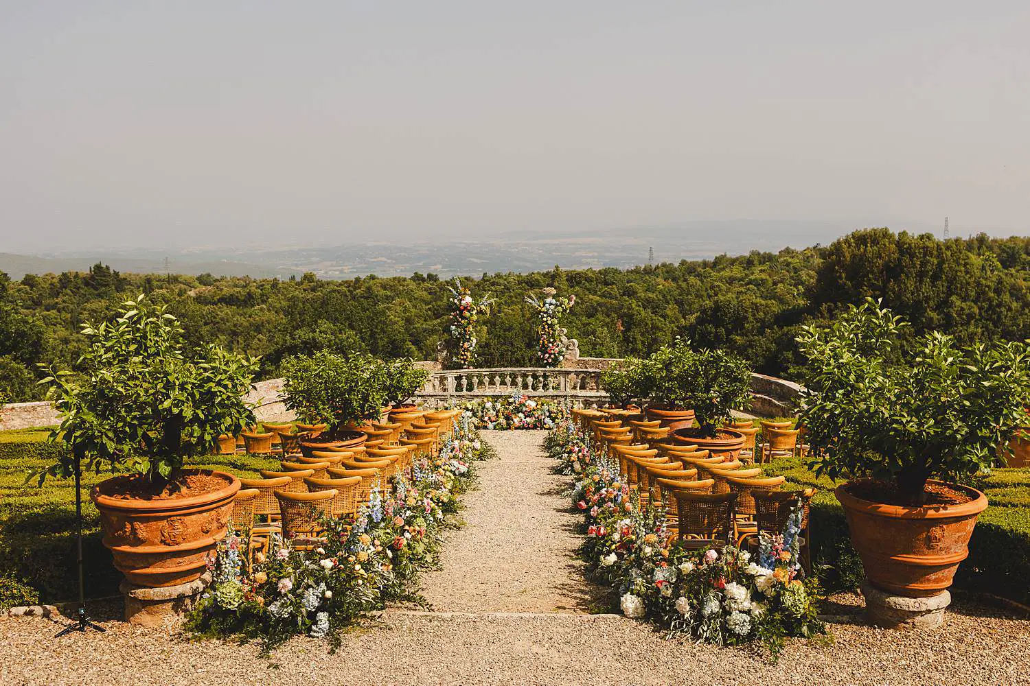 Elegant and colourful wedding ceremony setup in the garden of ancient Castello di Celsa in Tuscany