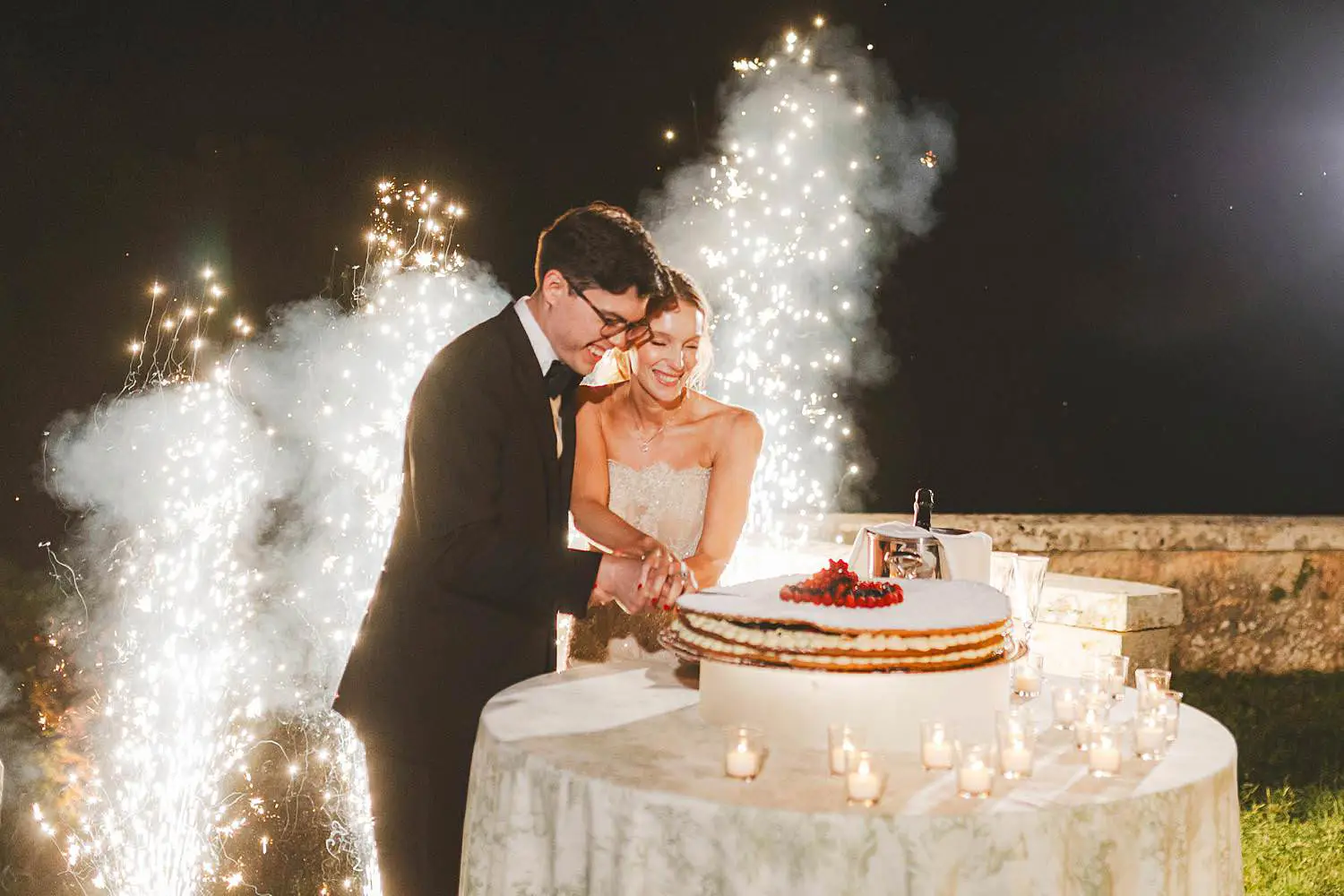 Exciting bride and groom cut of the cake with cold light fountains at Castello di Celsa wedding