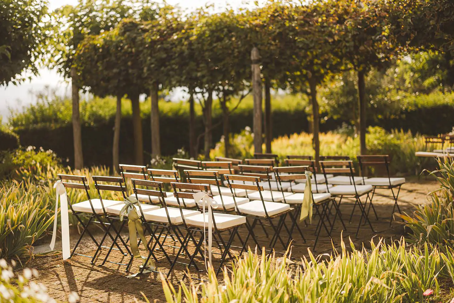 Outdoor same sex wedding ceremony decor among a natural archway of greenery and rustic stone architecture at Borgo di Petrognano