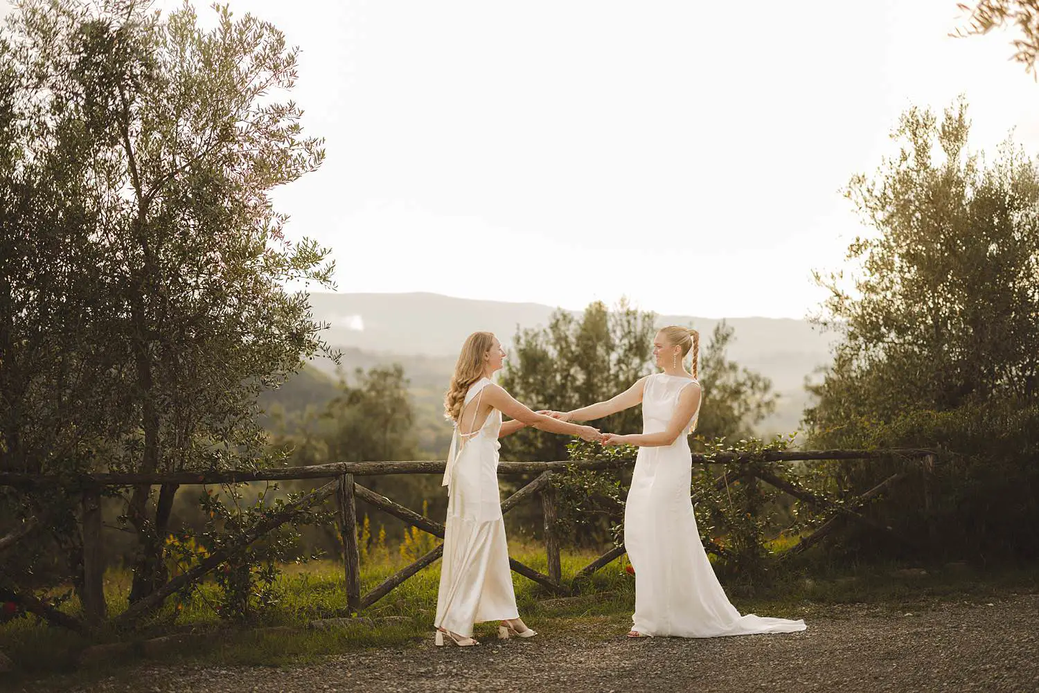 Intimate same sex destination wedding portrait surrounded by rolling hills, olive trees and warm autumn light at Borgo di Petrognano