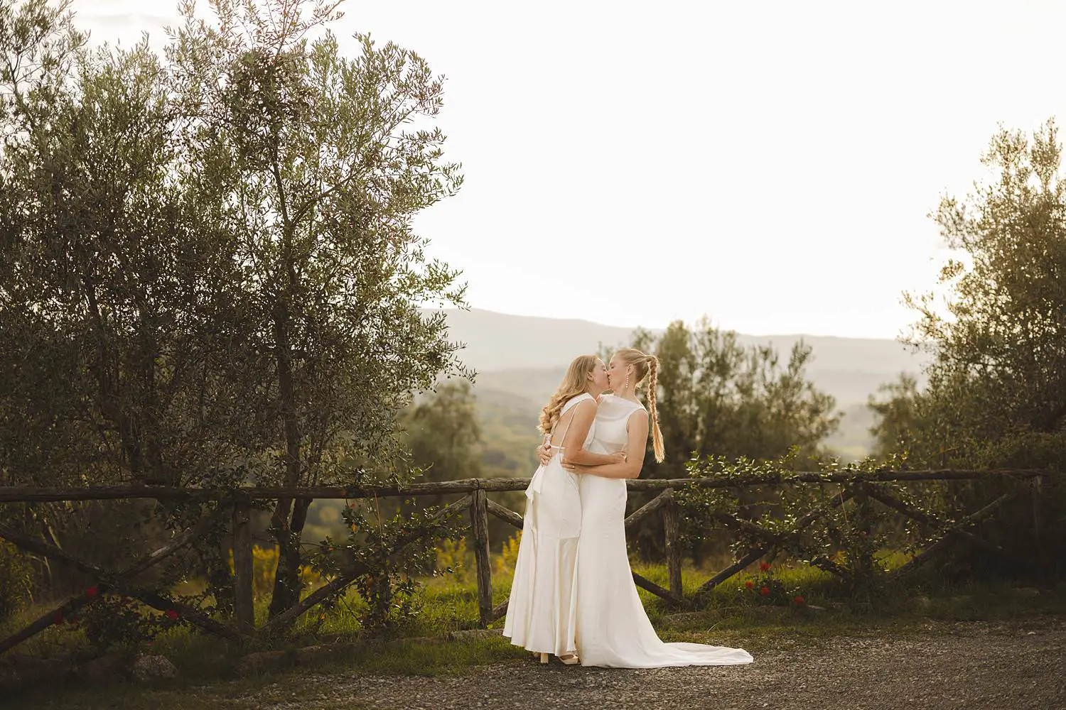 Intimate same sex destination wedding portrait surrounded by rolling hills, olive trees and warm autumn light at Borgo di Petrognano