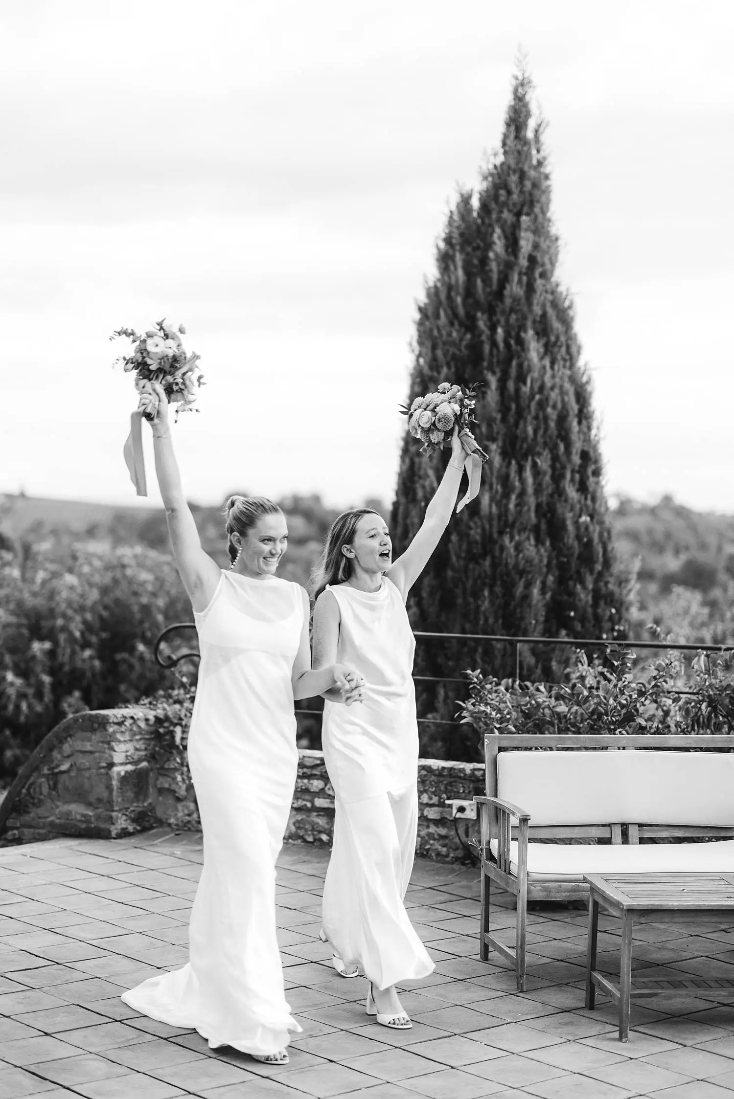 Same sex brides make a joyful entrance to dinner, greeted by applause, laughter and waving napkins at Borgo di Petrognano