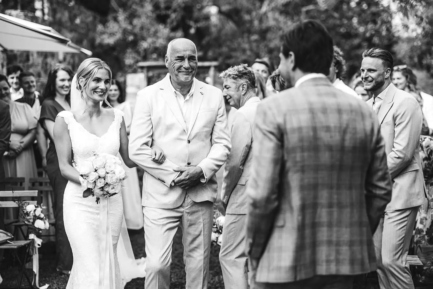 Emotional bride and father walk in the outdoor wedding ceremony at Agriturismo Quercia al Poggio