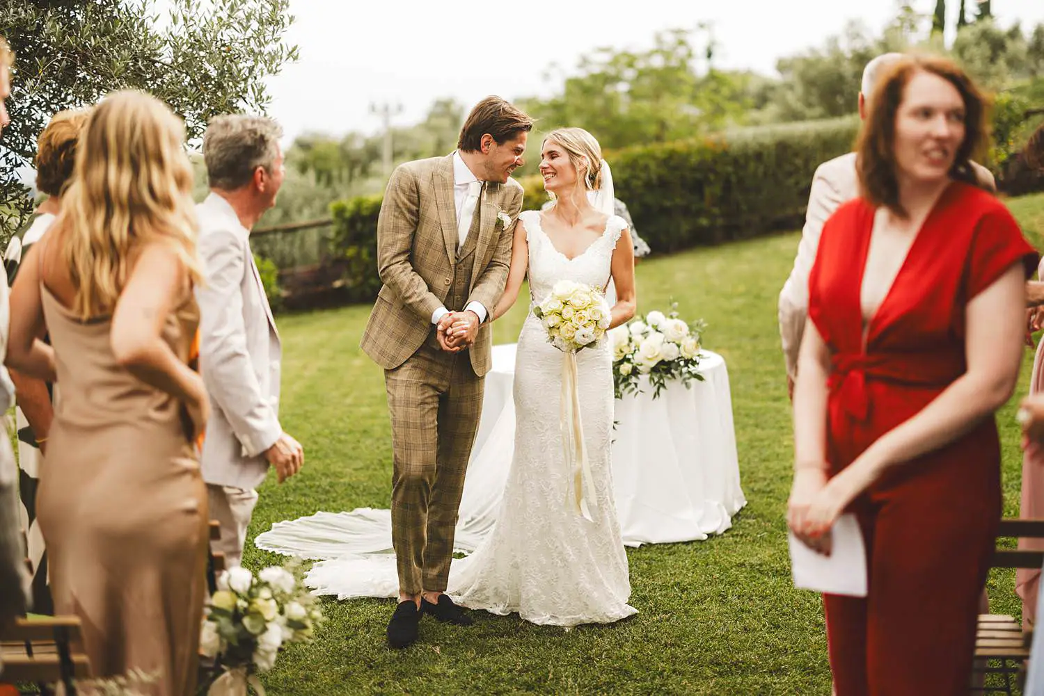 Smiling and excited bride and groom while walking out the outdoor wedding ceremony at Agriturismo Quercia al Poggio