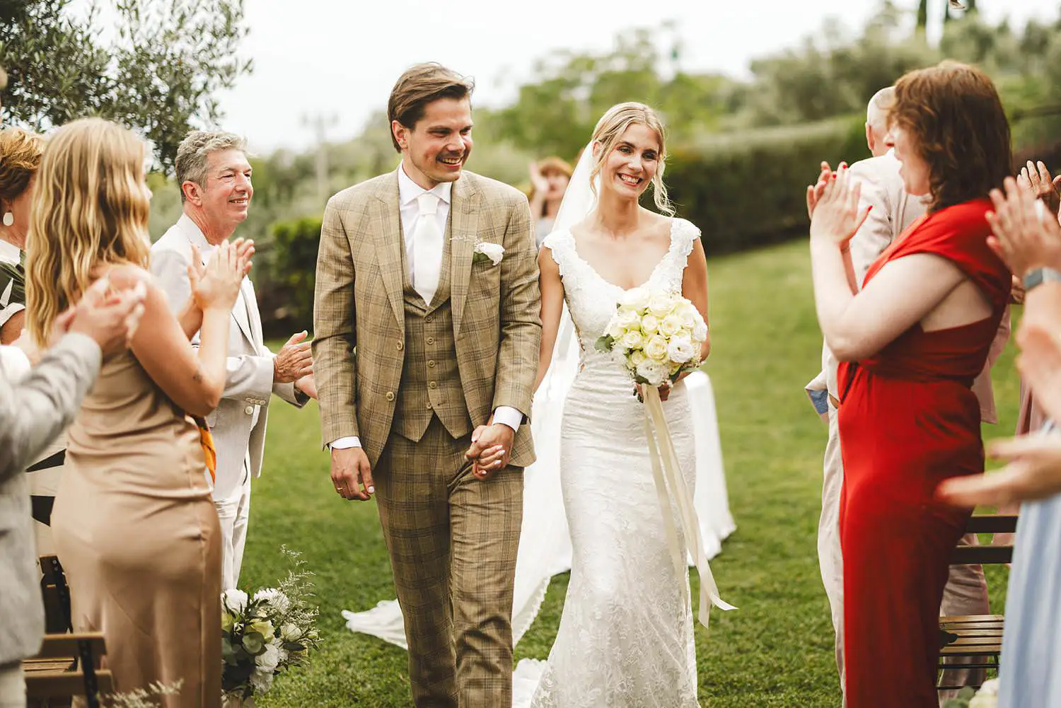 Smiling and excited bride and groom while walking out the outdoor wedding ceremony at Agriturismo Quercia al Poggio