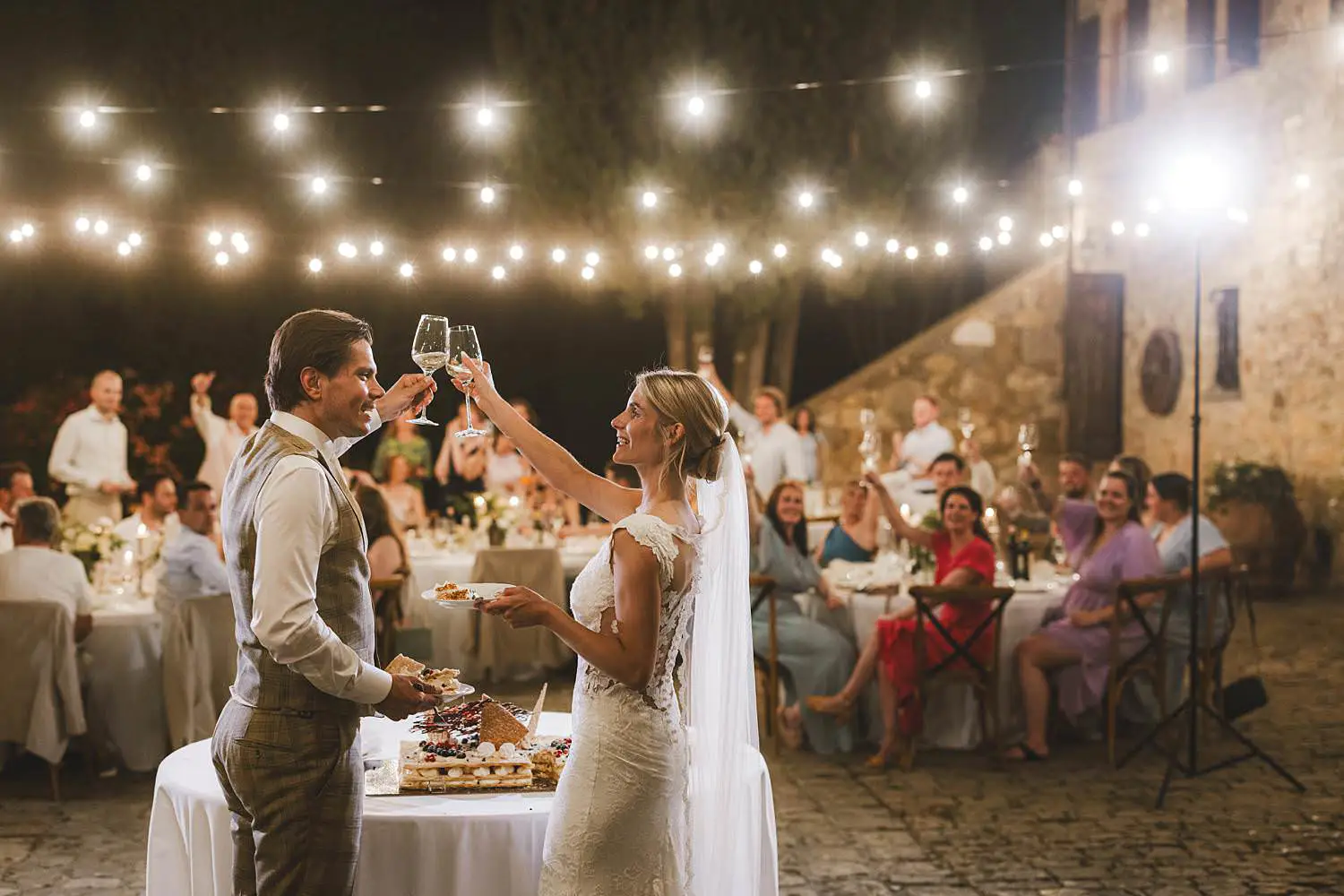 Timeless and unforgettable cut of the cake by bride and groom at courtyard of Agriturismo Quercia al Poggio wedding