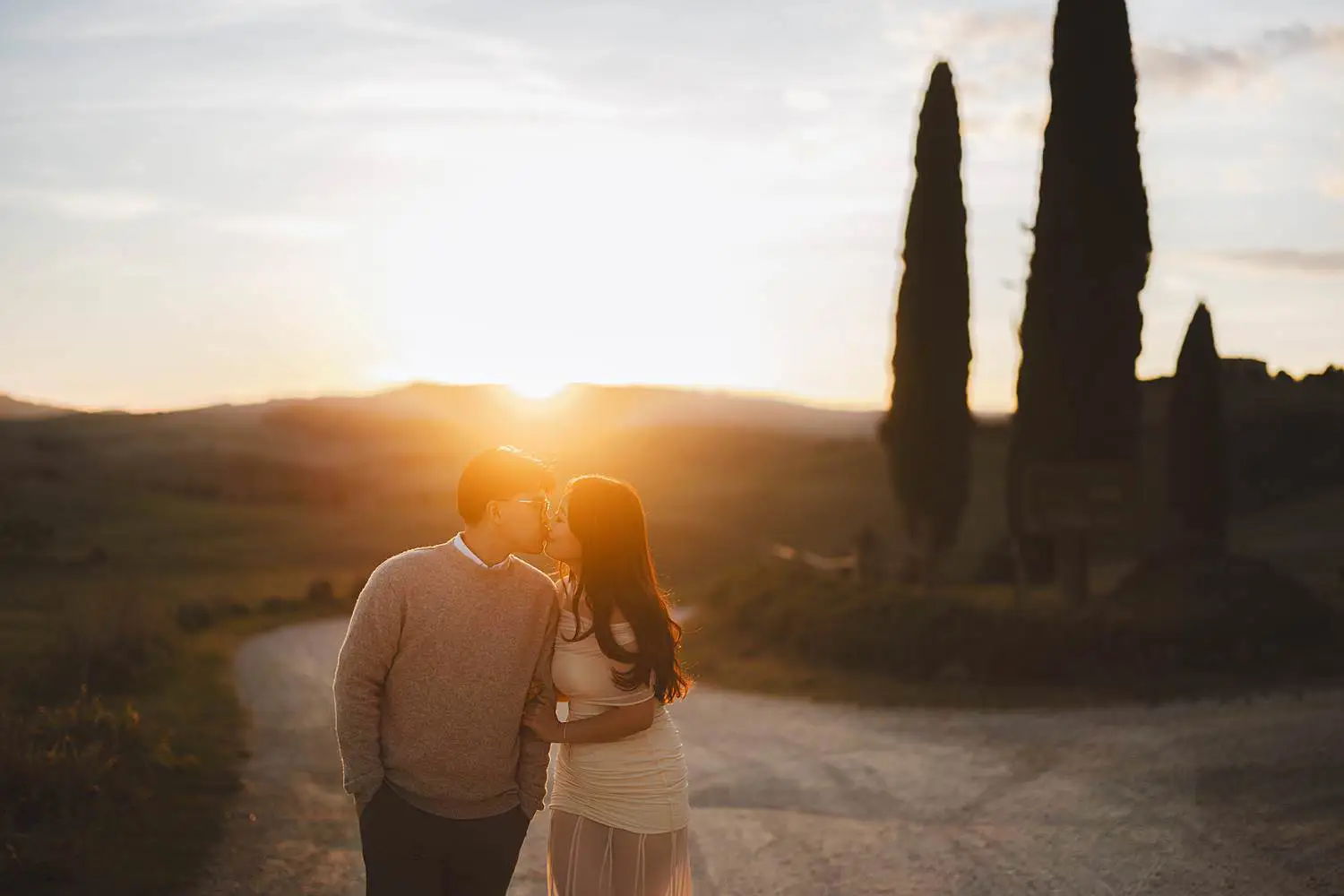 Romantic and dreaming engagement photo shoot in the iconic Tuscan landscapes near Pienza with cypresses trees