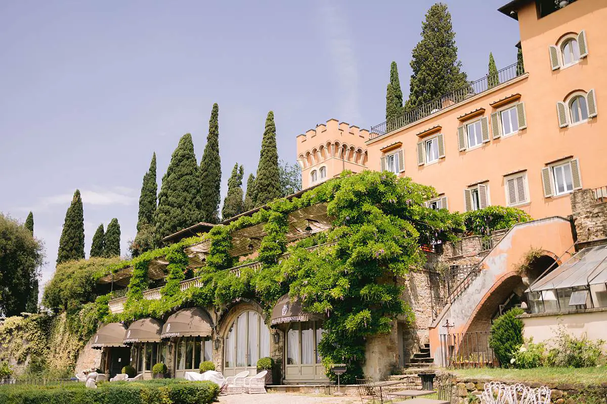 Exterior of Villa Le Fontanelle with cypress trees and vine-covered terraces in Florence, Tuscany.