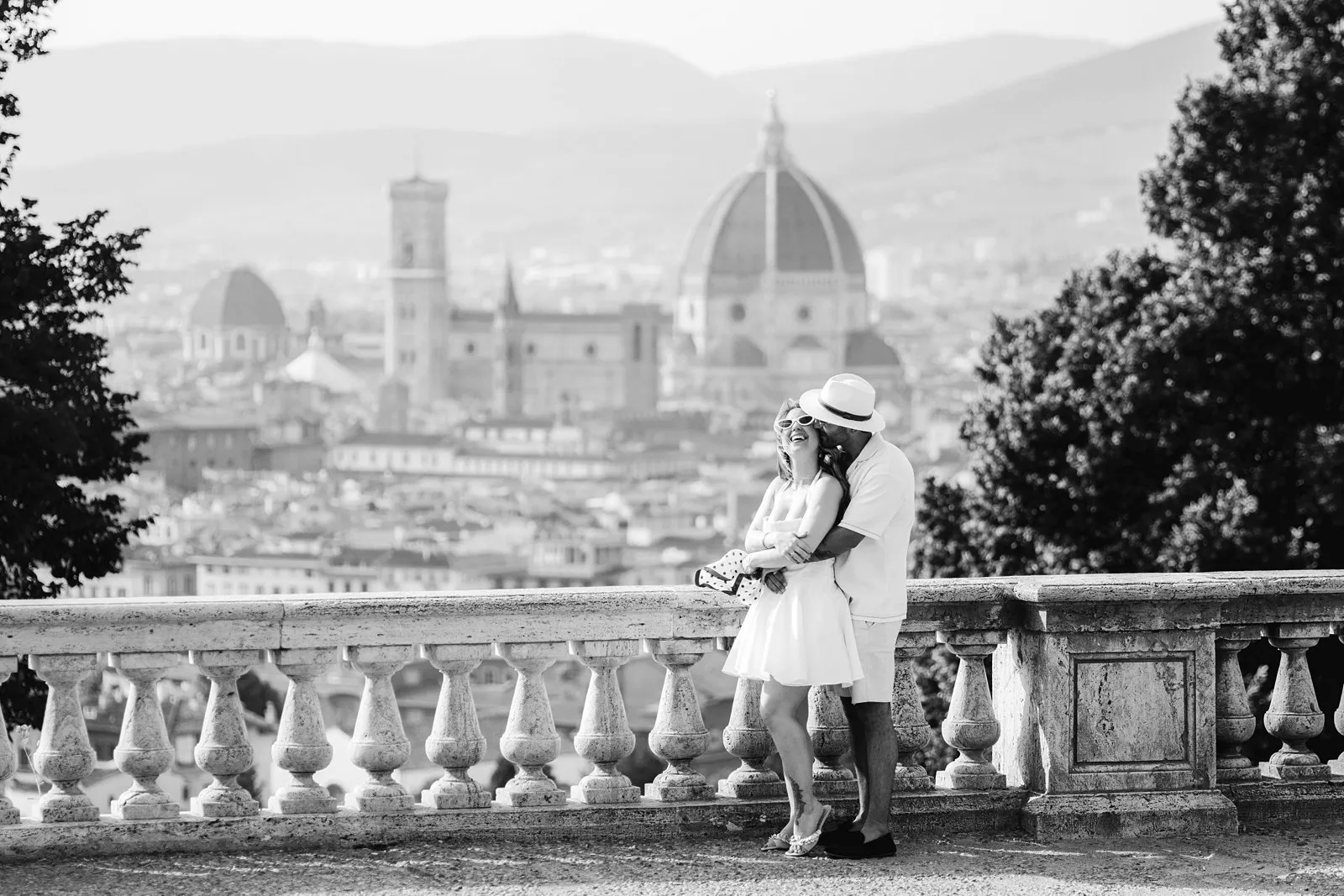 Black-and-white photograph of Leo embracing Nere beside a stone balustrade overlooking Florence and the Duomo.
