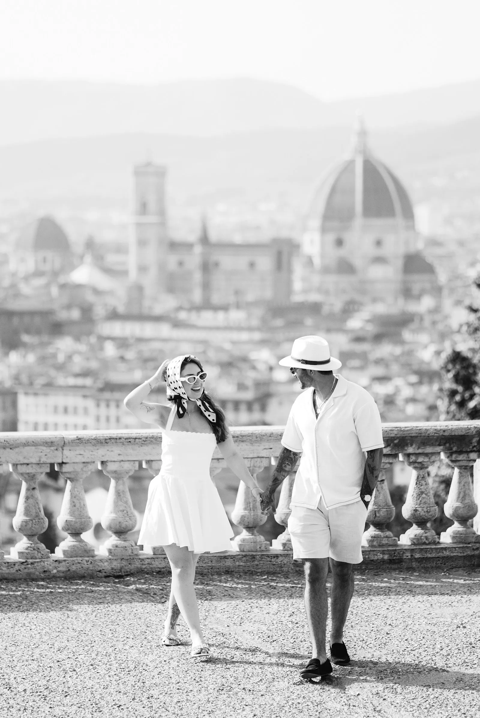 Black-and-white portrait of Nere and Leo walking hand in hand, with the dome of Florence Cathedral blurred behind them.