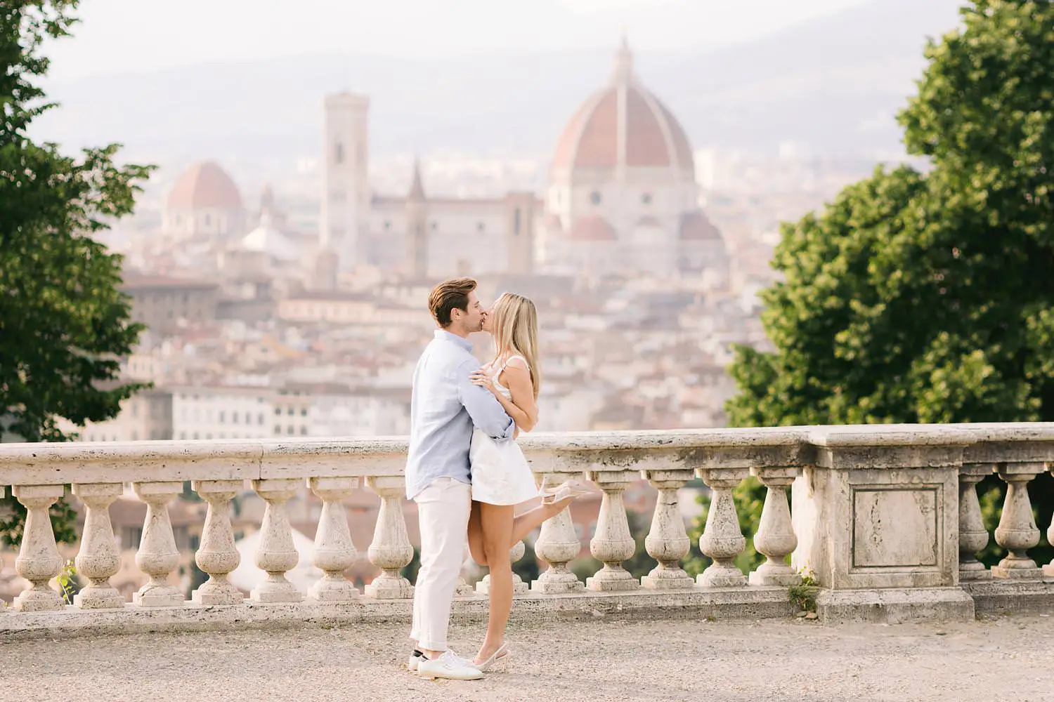 Couple kissing at San Miniato al Monte with Florence Cathedral behind them during a pre-wedding photoshoot.