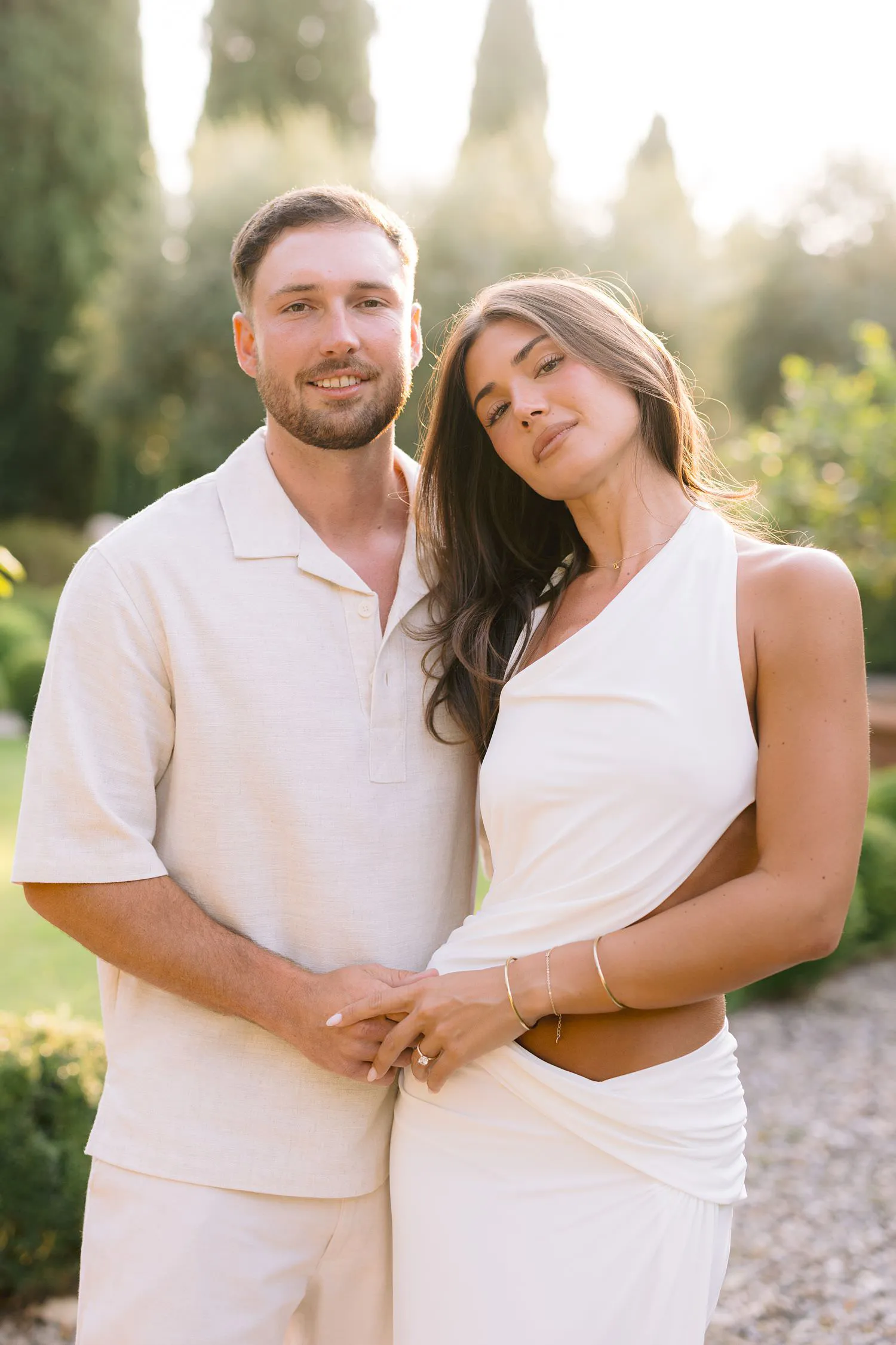 The newly engaged couple posing together, her head resting against his, in the castle gardens.