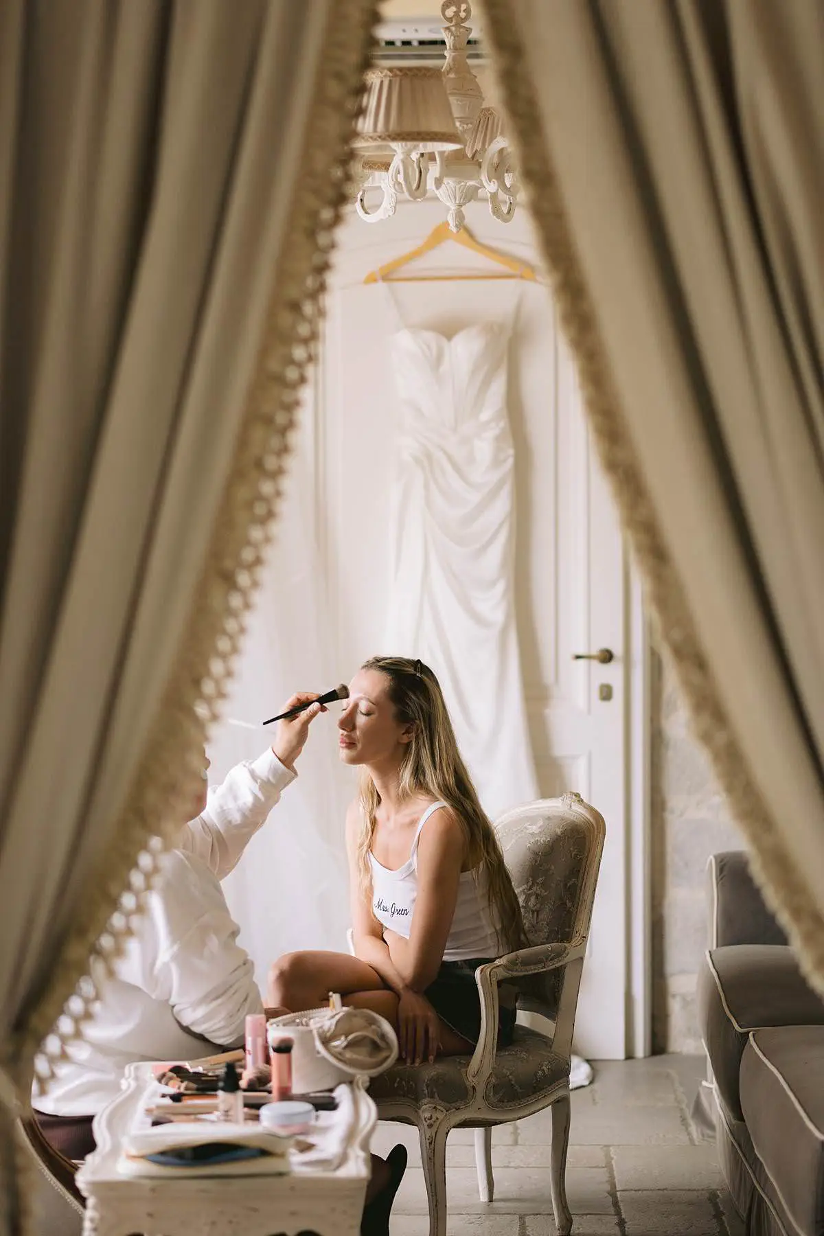 Bride having makeup applied as her wedding dress hangs behind her at Villa Le Fontanelle.