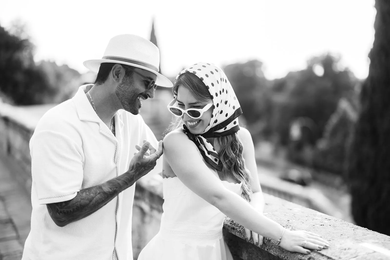 Black-and-white close portrait of Nere and Leo laughing together beside a stone balustrade in Florence.