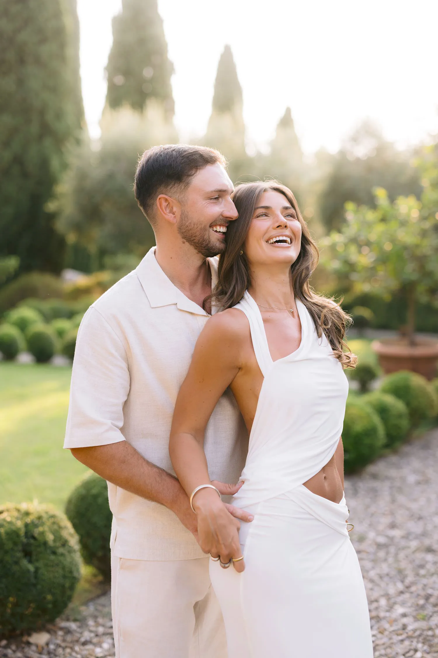 The couple laughing together during an embrace in the gardens.