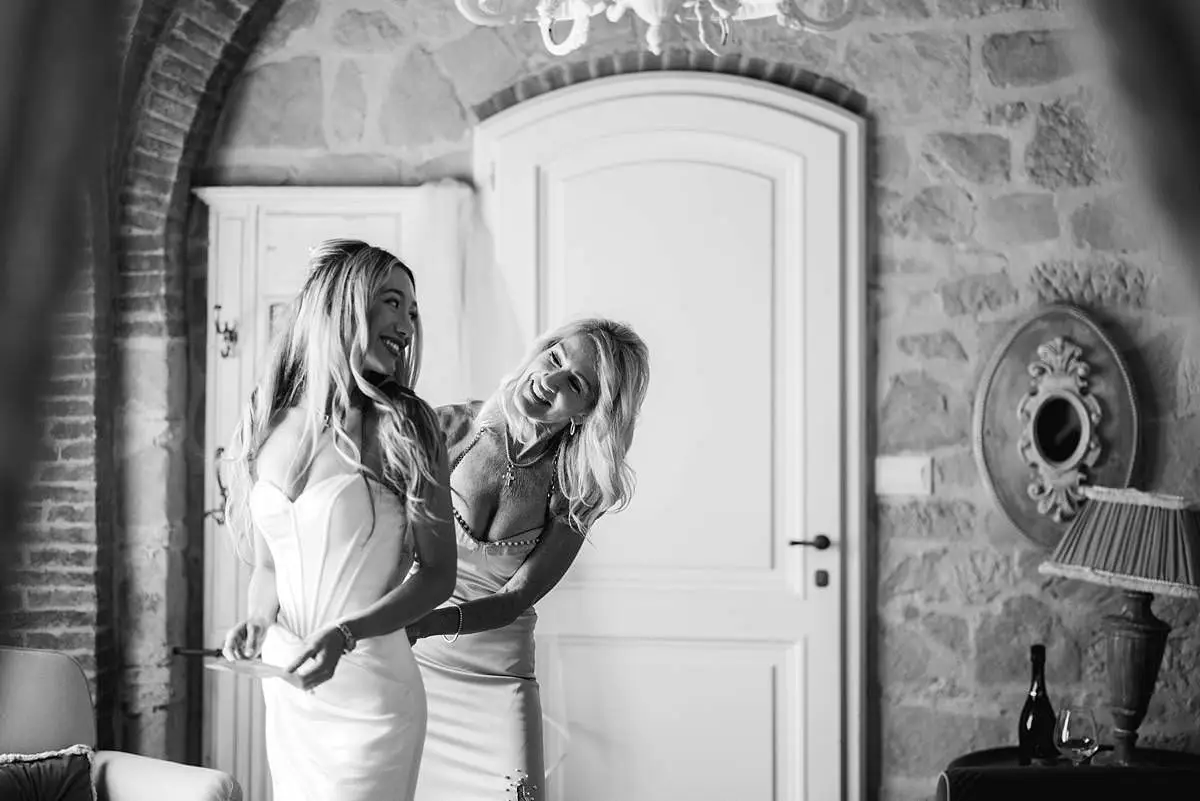 Mother helps the bride into her white wedding dress during preparations at Villa Le Fontanelle.