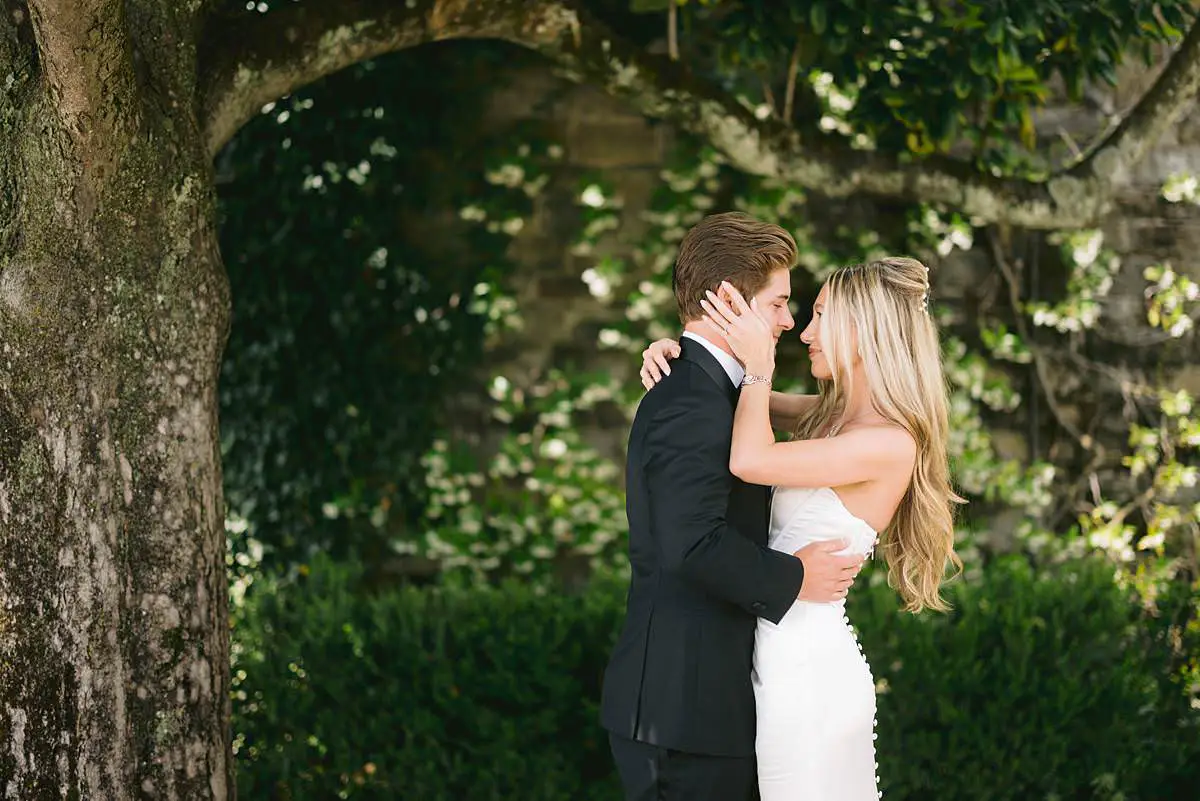 Madison and Travis embrace beneath a tree during their first look in the gardens of Villa Le Fontanelle, Florence.