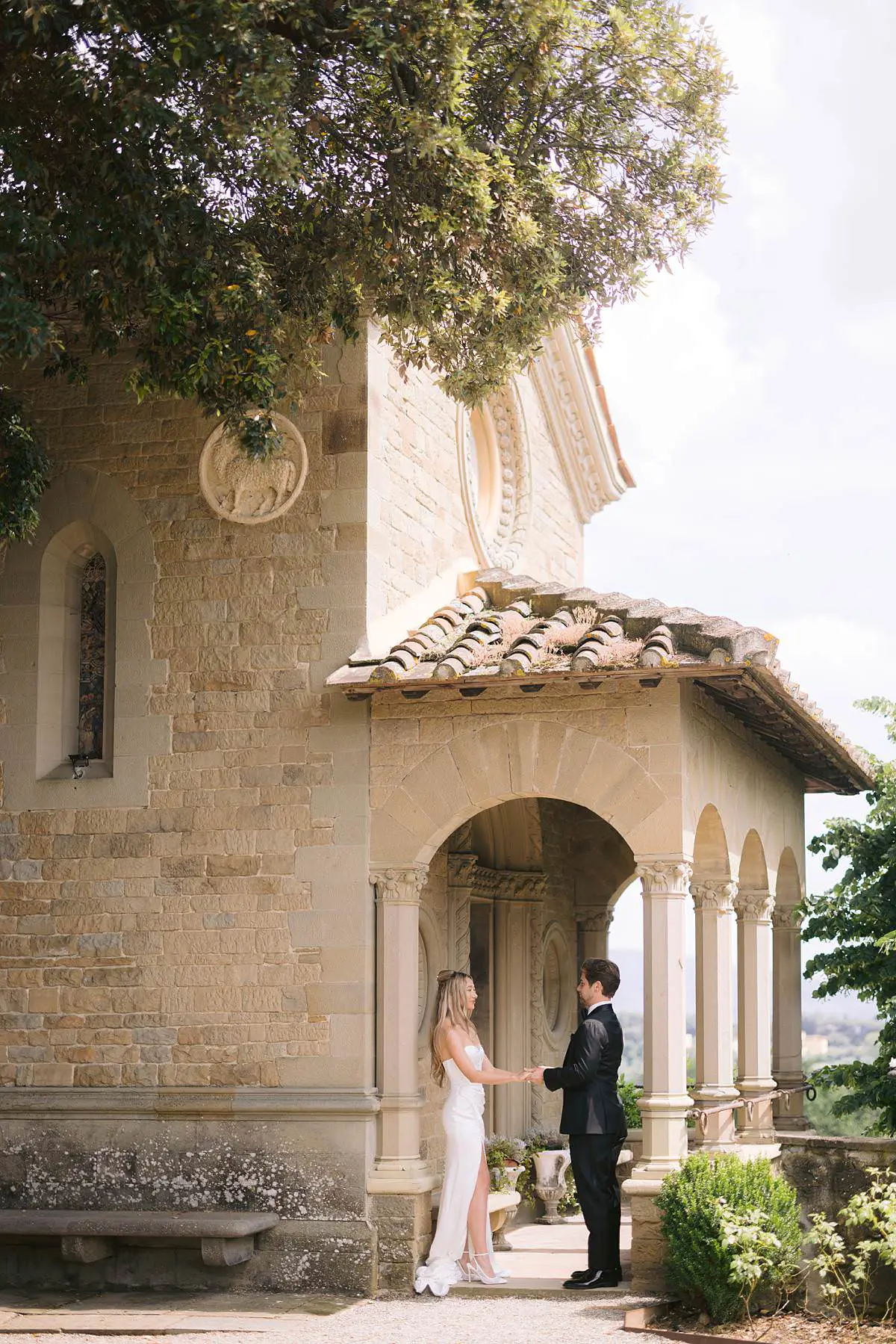 Madison and Travis hold hands outside the chapel at Villa Le Fontanelle in Florence, Tuscany.