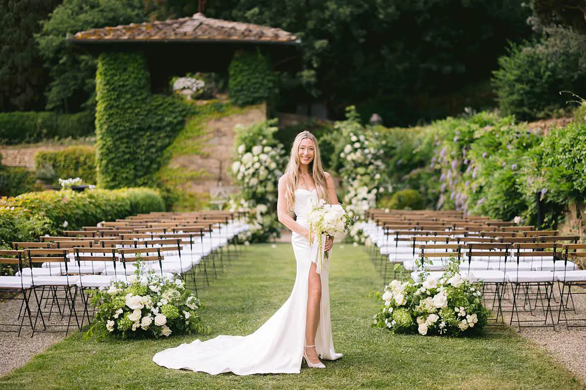 Bride holding a white bouquet in the garden ceremony aisle at Villa Le Fontanelle.