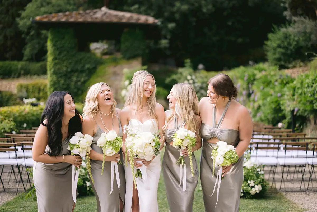 Bride and bridesmaids pose with white bouquets in the Villa Le Fontanelle garden.