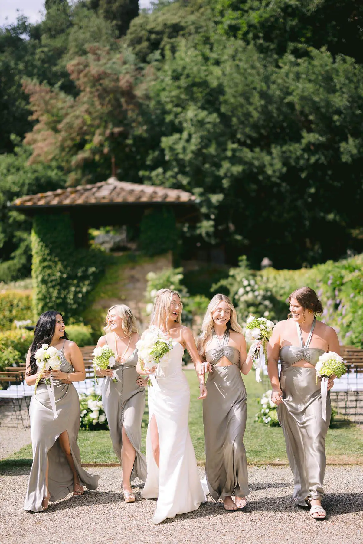 Bride and bridesmaids walk together in the Villa Le Fontanelle garden before the ceremony.