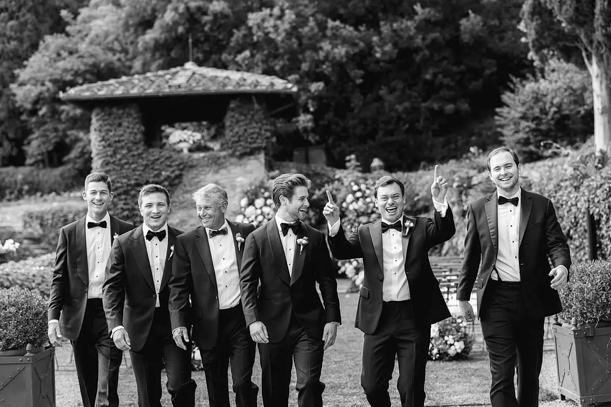 Groom and groomsmen in tuxedos celebrate in the Villa Le Fontanelle garden.